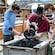 2 young men watching a historic reenactor pan for gold